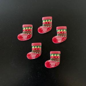 May include: Five red and green Christmas stocking buttons with a white background.