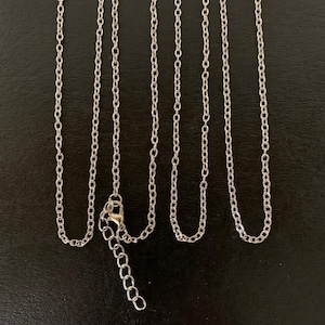 May include: A silver-toned metal chain necklace featuring a series of uniform oval links. The necklace includes a lobster claw clasp and an adjustable extender chain with larger links at the end, allowing for a customizable length for the wearer.