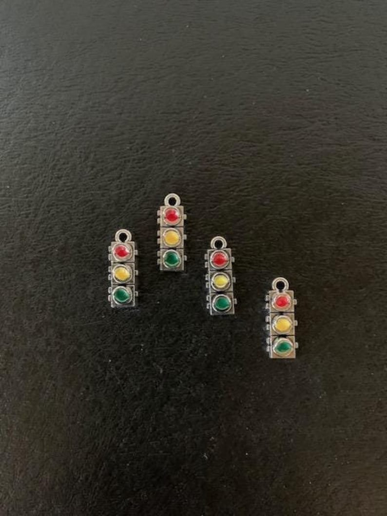 May include: Four silver charm pendants shaped like traffic lights with red, yellow, and green glass beads.