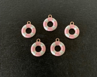 May include: Five small, round charms in a life preserver design. Each charm features a pink and white color scheme with a gold-colored loop at the top for attaching to jewelry or other crafts. The charms are arranged on a dark surface.