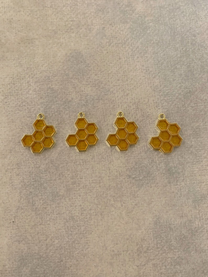 Puede incluir: Cuatro abalorios de metal de color dorado con forma de panales. Cada abalorio tiene un bucle en la parte superior para sujetarlo a un collar o una pulsera.
