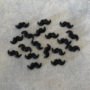 May include: A collection of black rhinestone mustache embellishments.