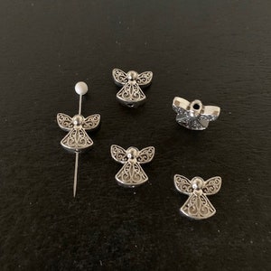 May include: Five silver angel charms with intricate designs. The charms are small and delicate, perfect for adding a touch of elegance to jewelry or crafts.