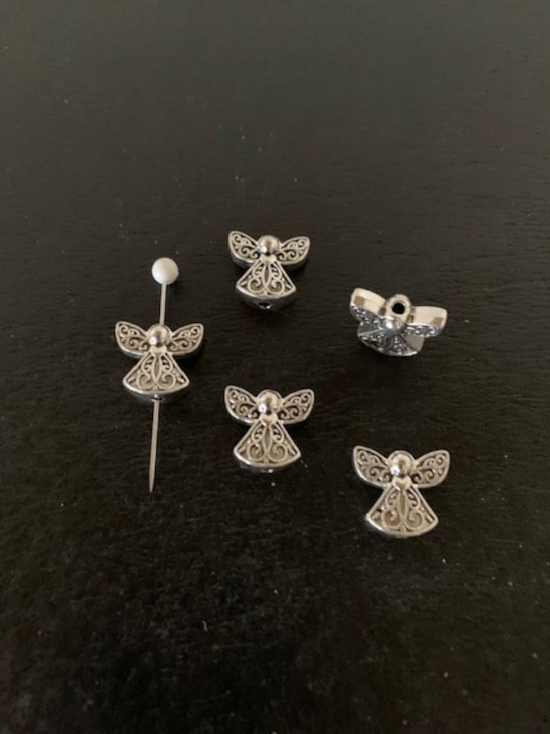 May include: Five silver angel charms with intricate designs. The charms are small and delicate, perfect for adding a touch of elegance to jewelry or crafts.