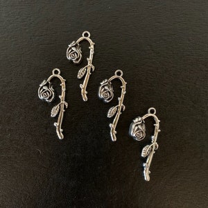 May include: Four silver rose stem charms with a single rose on each stem. The charms are perfect for adding a touch of elegance to jewelry or crafts.