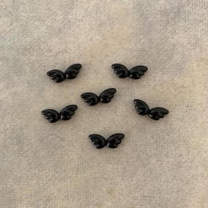 May include: Six black plastic angel wings, each with a slightly different shape and size.