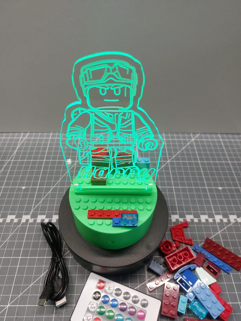 May include: A green LED night light in the shape of a Lego figure, with the name "Harry" etched into the acrylic. The light sits on a green base with Lego bricks and includes a remote control and USB cable.