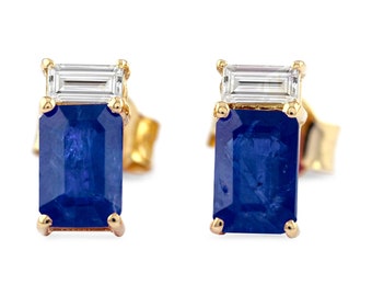 May include: A pair of gold earrings with a blue sapphire and a clear diamond. The sapphire is an emerald cut and the diamond is a baguette cut.