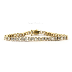 May include: A gold bracelet with a row of emerald-cut diamonds. The bracelet is made of 14k gold and features a secure clasp.
