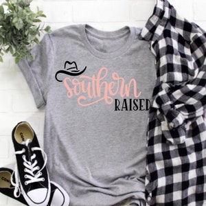 May include: A gray t-shirt with a black cowboy hat graphic and the text "Southern Raised" in pink lettering.