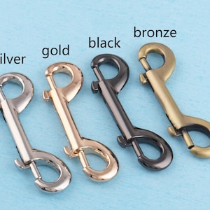 May include: Five swivel snap hooks in different colors: silver, gold, black, bronze, and a lighter bronze. The hooks are all the same size and shape.