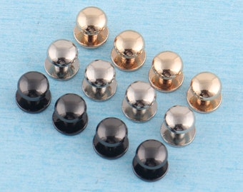 Puede incluir: Surtido de pomos redondos de metal en acabados negro, plateado y dorado. Los pomos tienen una parte superior abovedada y una base plana.