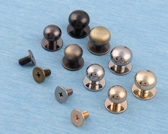 Könnte beinhalten: Sortiment an Metallknöpfen in verschiedenen Ausführungen, darunter Gold, Silber und Schwarz. Die Knöpfe sind rund und für Möbel oder andere Bastelarbeiten gedacht.  Im Lieferumfang sind Schrauben zur Befestigung der Knöpfe enthalten.