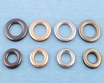 May include: Eight metal grommets in various finishes, including silver, gold, and black. The grommets are arranged in two rows of four.