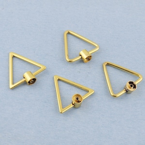 May include: Four gold-coloured, triangular carabiner clasps. Each clasp has a screw-lock mechanism and a small, cylindrical barrel. The clasps are arranged on a light blue surface, showcasing their geometric design and metallic finish.
