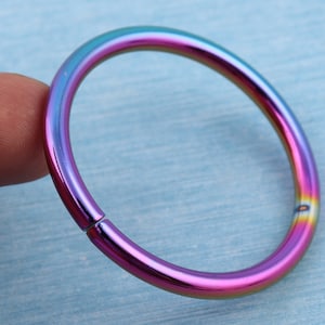 May include: A rainbow-colored metal ring with a seamless finish. The ring is open and has a smooth, polished surface.