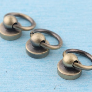 K&ouml;nnte beinhalten: Drei antike goldfarbene Metallringe mit einem kugelf&ouml;rmigen Drehgelenk. Jeder Ring hat eine flache Basis.