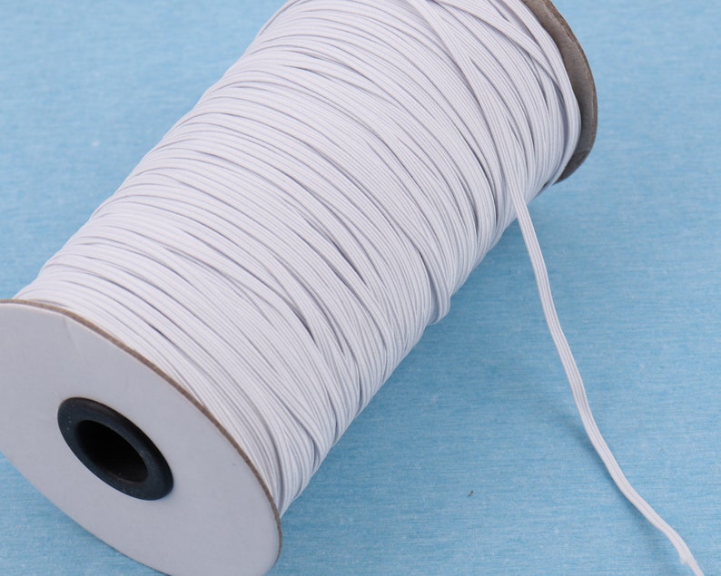 Puede incluir: Una bobina de cord&oacute;n el&aacute;stico blanco, enrollada alrededor de un n&uacute;cleo de cart&oacute;n. El cord&oacute;n se utiliza para coser y proyectos de artesan&iacute;a.