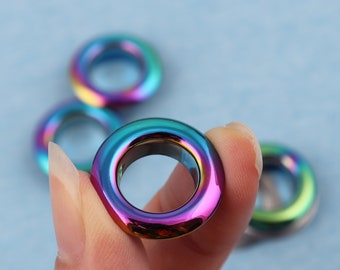 Op de afbeelding: Een set regenboogkleurige, iriserende metalen oogjes. De oogjes zijn rond en hebben een gat in het midden. Ze zijn perfect om een vleugje kleur en stijl aan je knutselwerk toe te voegen.