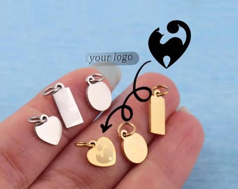 May include: A collection of small metal jewelry charms in silver and gold tones, featuring heart, rectangular, and circular shapes with jump rings. A graphic of a cat silhouette and the text your logo are displayed above the charms.
