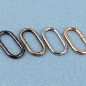 May include: Four oval-shaped metal rings in black, bronze, silver, and gold.