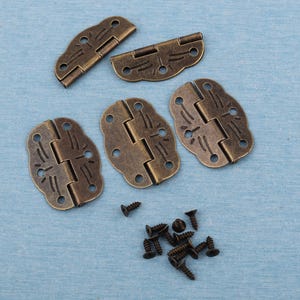 Puede incluir: Bisagras de color bronce antiguo con diseños florales decorativos y tornillos a juego. Las bisagras se muestran en varias posiciones abiertas y cerradas. Ideales para pequeñas cajas o proyectos decorativos.