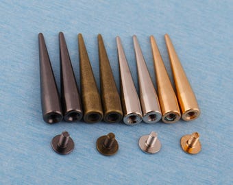 May include: A collection of cone-shaped metal studs in various colors, including gunmetal, bronze, silver, and gold. Each stud has a pointed tip and a threaded base, with matching screw-back fasteners. These decorative studs are ideal for leathercraft and DIY projects.