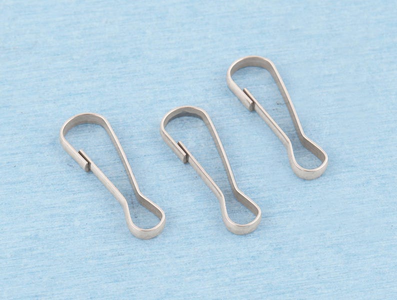 May include: Three silver-toned metal lanyard hooks, each featuring a teardrop-shaped loop at the base and a spring-loaded gate mechanism at the top, designed for attaching items securely to keychains, bags, or other accessories.