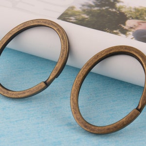 May include: Two antique gold-toned metal key rings. The key rings are round and have a smooth finish.