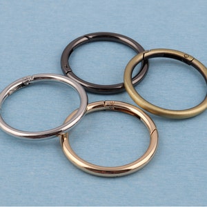 Könnte beinhalten: Vier Schlüsselringe aus Metall in verschiedenen Ausführungen: Silber, Gold, Schwarz und Messing. Die Ringe sind alle offen und einsatzbereit.