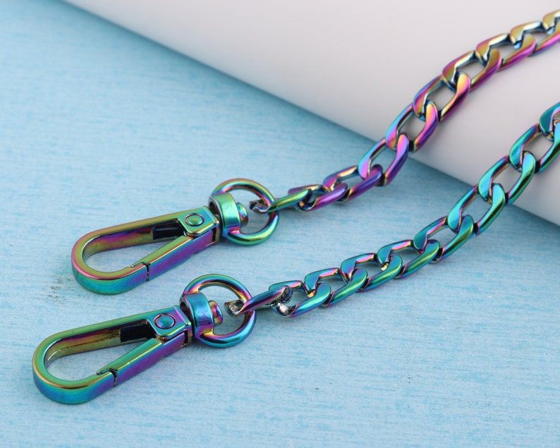 May include: A rainbow iridescent chain with two metal clasps. The chain is a curb style with a flat, rectangular link.