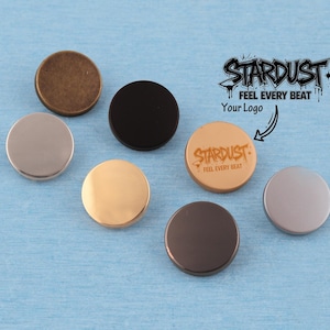 May include: Seven circular metal buttons in various finishes including bronze, matte black, polished gold, silver, and copper. One button features the engraved text STARDUST FEEL EVERY BEAT, which matches the logo graphic displayed in the upper right corner.