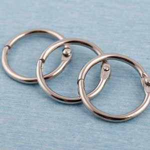 Puede incluir: Tres anillos de encuadernación de metal plateado. Los anillos están entrelazados y están diseñados para sujetar papeles juntos.