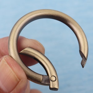 May include: A gold-toned metal key ring with a spring-loaded clasp. The ring is open and ready to be used.