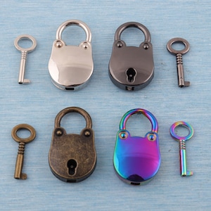 Peut inclure: Divers cadenas décoratifs et clés aux finitions métalliques variées. Les cadenas sont argentés, noirs, bronze et irisés arc-en-ciel. Les clés assorties créent une esthétique vintage ou steampunk.