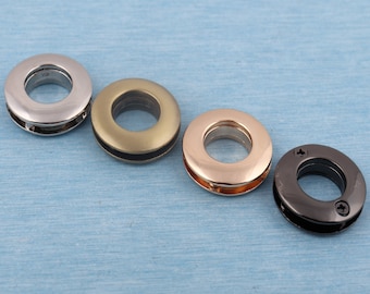 May include: Four metal grommets in different finishes: silver, gold, brass, and black. The grommets are round with a hole in the center.