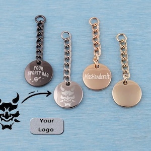 May include: Four circular metal tags with attached chains in black, silver, rose gold, and gold finishes. The black tag features the text "YOUR SPORTY BAG" with a baseball icon, the silver tag displays a demon mask graphic, and the rose gold tag reads "MissHandcraft".