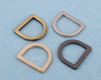 May include: Four metal D-rings in different finishes: gold, silver, nickel, and black. These rings are commonly used for attaching straps, chains, or other hardware to bags, belts, or other accessories.