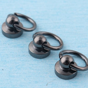 K&ouml;nnte beinhalten: Drei schwarze Metallringe mit einer Kugel und einer Basis. Die Ringe sind in verschiedenen Gr&ouml;&szlig;en.