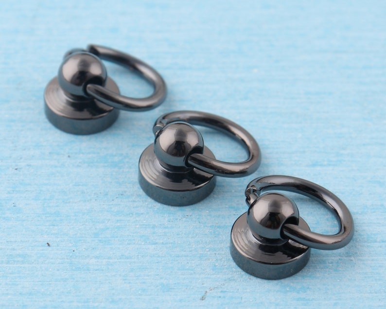 K&ouml;nnte beinhalten: Drei schwarze Metallringe mit einer Kugel und einer Basis. Die Ringe sind in verschiedenen Gr&ouml;&szlig;en.