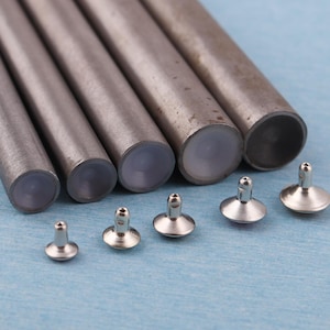 May include: A collection of silver-colored metal rivets and tubes. The tubes are cylindrical with a slightly worn appearance. The rivets have a flat, circular head and a short, cylindrical post. The background is a light blue.