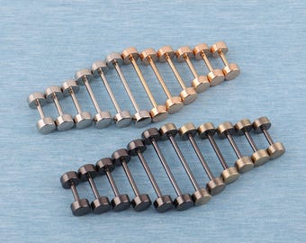 May include: An assortment of stud earrings in various metallic finishes, including silver, gold, rose gold, and gunmetal. The earrings are arranged in rows on a light blue surface, showcasing their dumbbell-like design.