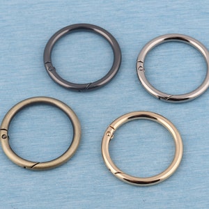 May include: Four metal key rings in different finishes: black, bronze, silver, and gold. Each ring has a spring-loaded clasp.
