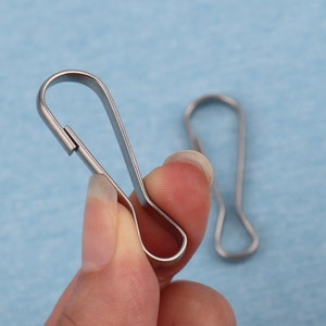 May include: Two silver metal key rings with a swivel clasp. The key rings are in the shape of a loop.