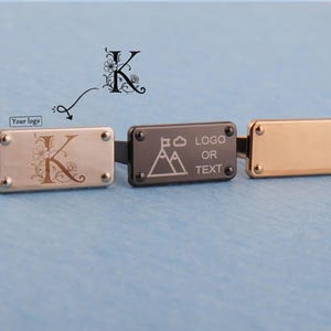 May include: Three metal cufflinks with rectangular faces. One cufflink is silver with an engraved floral "K". Another is dark gray with a mountain graphic and the text "LOGO OR TEXT". The third is gold. All have silver rivets.