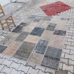 May include: A patchwork rug with a variety of colors and patterns, including beige, brown, gray, and blue. The rug is made of different pieces of fabric that have been sewn together.