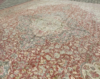 May include: A vintage rug with a faded red, cream, and green floral pattern. The rug has a distressed look and is made of a woven material.