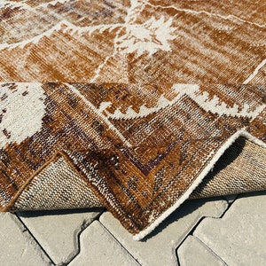 Puede incluir: Una alfombra de color marr&oacute;n y blanco con un borde de flecos. La alfombra est&aacute; doblada por la mitad y se ve la parte inferior.
