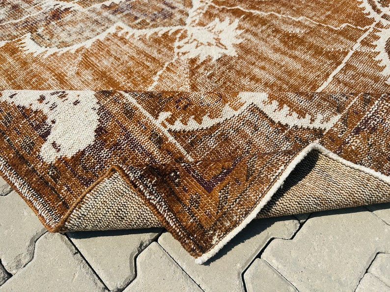 Puede incluir: Una alfombra de color marr&oacute;n y blanco con un borde de flecos. La alfombra est&aacute; doblada por la mitad y se ve la parte inferior.