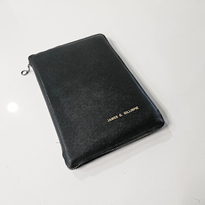 May include: Black rectangular case with a zipper closure and a silver pull. The text "JAMES G. GILLESPIE" is printed in gold on the front. The case is likely made of leather or a similar material.